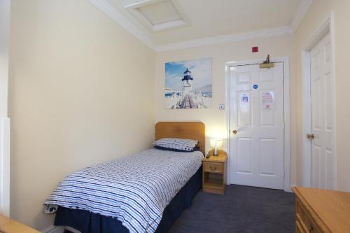 a small bedroom with a bed and a white door at Globe Inn in Tamworth