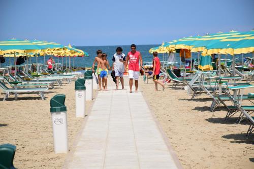 a group of people walking down a sidewalk on the beach at Hotel Houston in Rimini