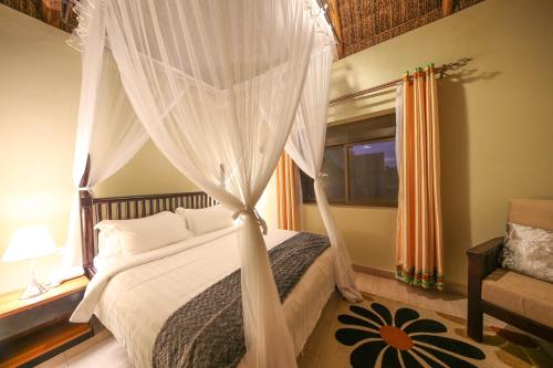 a bedroom with a canopy bed and a window at Victoria Forest Resort in Kalangala