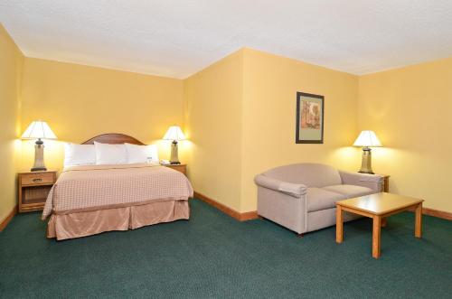 Habitación de hotel con cama y silla en Americas Best Value Inn Iola, en Iola