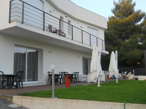 a house with a balcony with tables and umbrellas at Summer Beach Rooms in Fontane Bianche