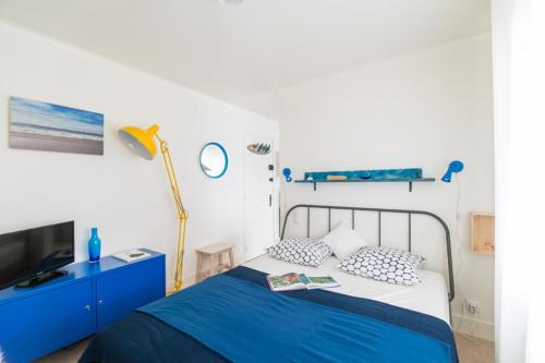 a blue and white bedroom with a bed and a tv at Le Studio Bleu de la gare in Vieux-Boucau-les-Bains