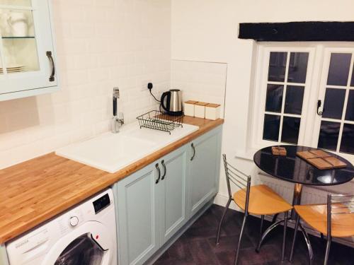 a kitchen with a sink and a table with chairs at Kenilworth Cosy Garden View Apartment in Kenilworth