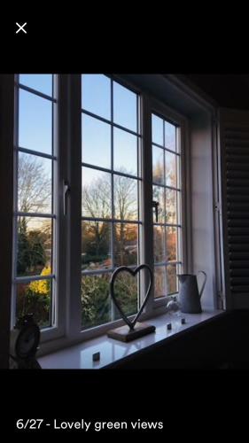 a window with two mirrors on a window sill at Kenilworth Cosy Garden View Apartment in Kenilworth