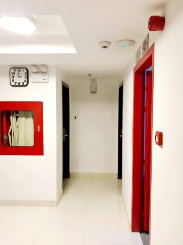 a hallway with a red door and a clock on a wall at Platinum Residence in Dhaka