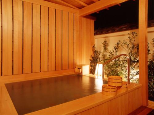 a bath tub in a wooden room with a sink at Atami Onsen Sakuraya Ryokan in Atami