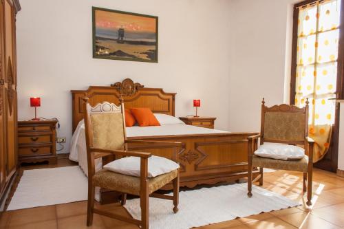 - une chambre avec un lit en bois et deux chaises dans l'établissement Is Cogas, à Masainas