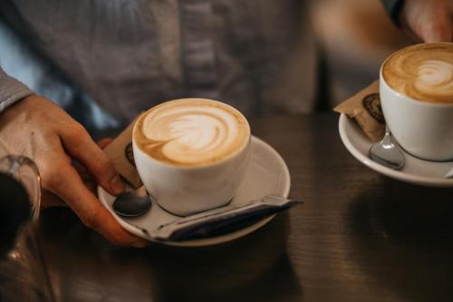 a person holding two cups of coffee on a table at Charlie's Bed & Breakfast in Antwerp