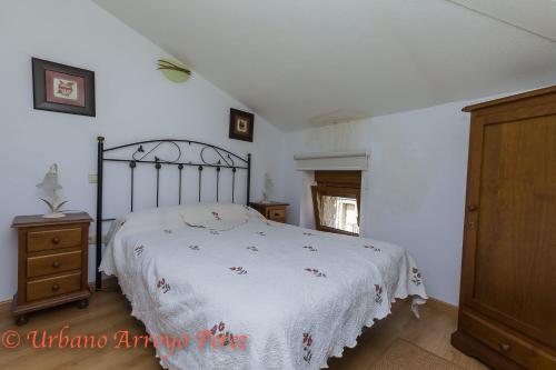 1 dormitorio con 1 cama con edredón blanco en Casa Rural El Salon del Baile, en Navarredondilla