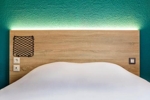 a headboard of a bed in a bedroom at hotelF1 Saint Etienne in Saint-Étienne