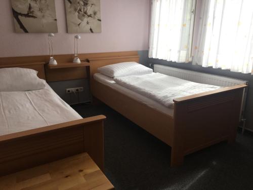 a bedroom with two beds and two windows at Pension Zum Angestellten in Porta Westfalica