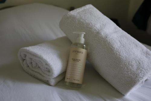 a bottle of moisturizers and towels on a bed at Absolute Hotel Paris République in Paris
