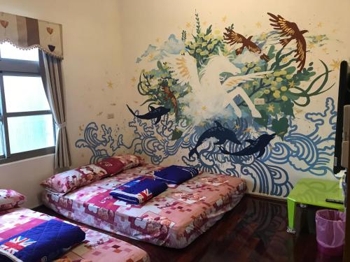 two beds in a room with a mural on the wall at Instructor 818 Rooms Homestay in Xiaoliuqiu