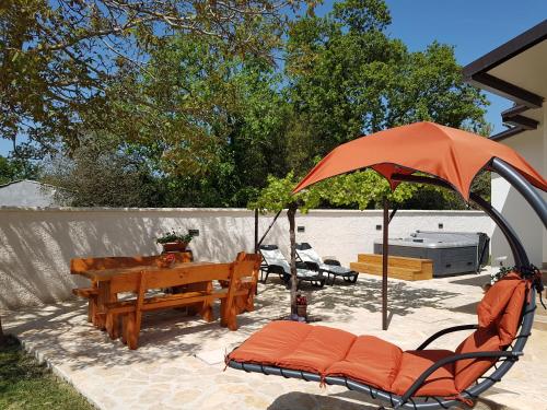 a patio with a table and benches and an umbrella at Holiday Home Kerniat in Pula