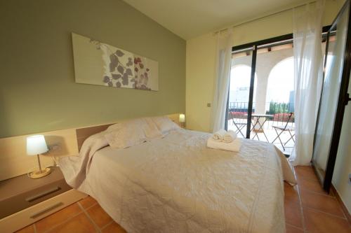 1 dormitorio con cama blanca y balcón en Iris en L'Ampolla