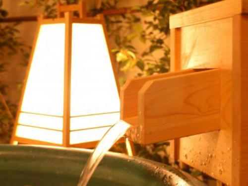 a lamp next to a bath tub with a water hose at Atami Onsen Sakuraya Ryokan in Atami