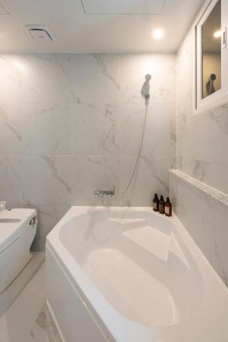 a white bathroom with a tub and a toilet at Seomyeon Brown-dot hotel Gold in Busan