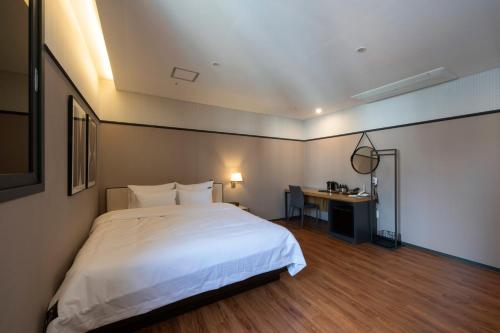 a bedroom with a large white bed and a desk at Seomyeon Brown-dot hotel Gold in Busan