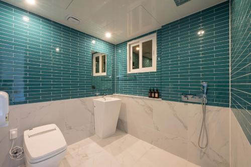 a bathroom with a toilet and a shower and blue tiles at Seomyeon Brown-dot hotel Gold in Busan