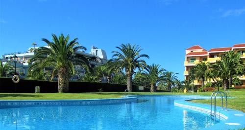 サンタ・ウルスラにあるOcean view La Quintaのヤシの木と建物が並ぶリゾート内のスイミングプール
