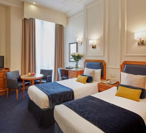 Habitación de hotel con 2 camas y escritorio en Lancaster Gate Hotel en Londres