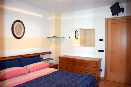 a bedroom with a bed and a dresser and a clock at Chiara in Roncegno