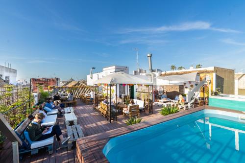 a beach with a pool, chairs, and tables at Oasis Backpackers' Palace Seville in Seville