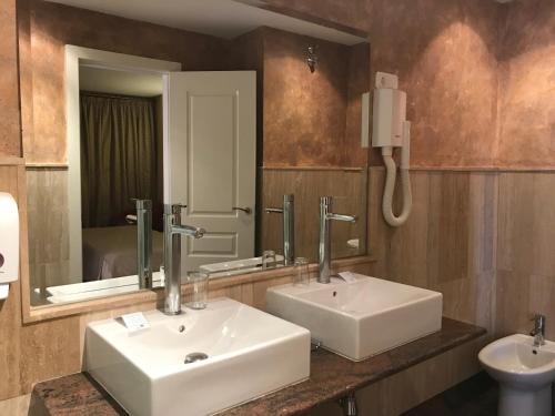 Un baño con dos lavabos y un espejo. en Hotel Alfonso VIII De Cuenca, en Cuenca