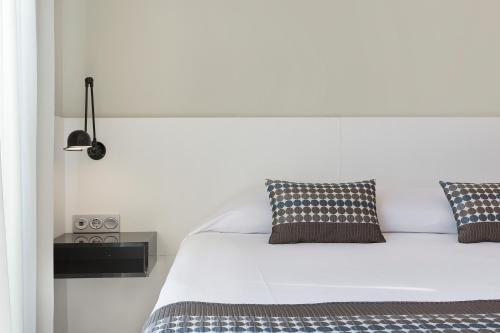 a white bed with two pillows in a bedroom at Aparthotel Odissea Park in Santa Susanna