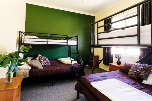 two bunk beds in a room with a green wall at Coal d' Vine Cottage - Cessnock NSW in Cessnock