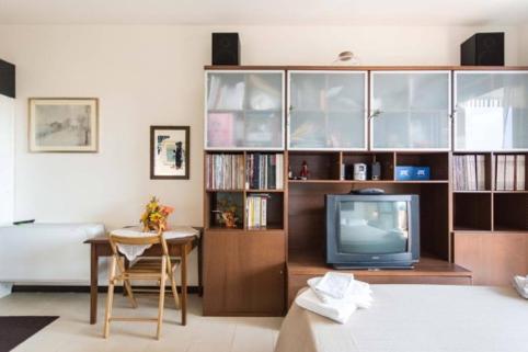 a living room with a television and a book shelf at Suite Carpiano in Melegnano