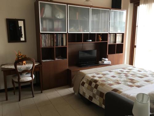 a bedroom with a bed and a desk with a television at Suite Carpiano in Melegnano