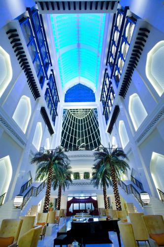 a lobby with two palm trees in a building at Bab Al Qasr Hotel in Abu Dhabi