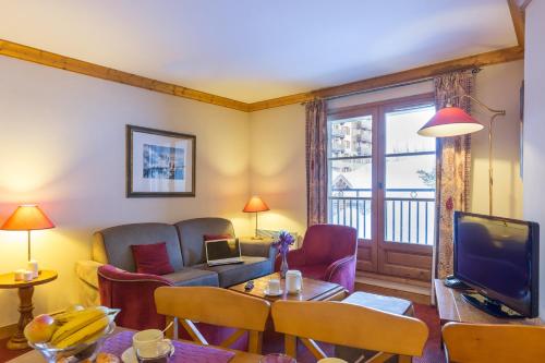 a living room with a couch and a table and a television at Résidence Pierre & Vacances Premium Arc 1950 Le Village in Arc 1950