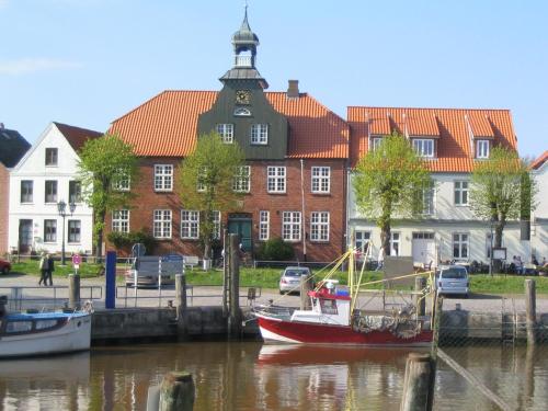a boat in the water in front of a building at Landhaus Pfahlershof in Karolinenkoog