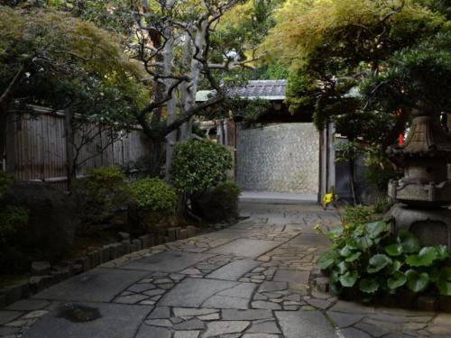 a garden with a stone walkway with a tree at Atami Onsen Sakuraya Ryokan in Atami