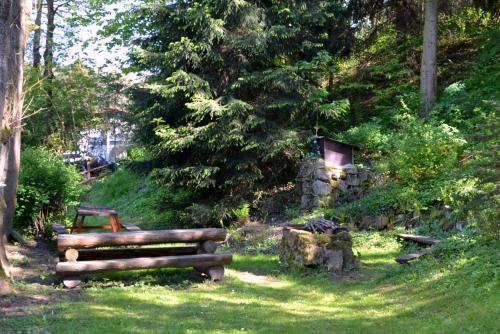 a wooden bench sitting in the grass near trees at Chalupa Bumbálka in Mníšek