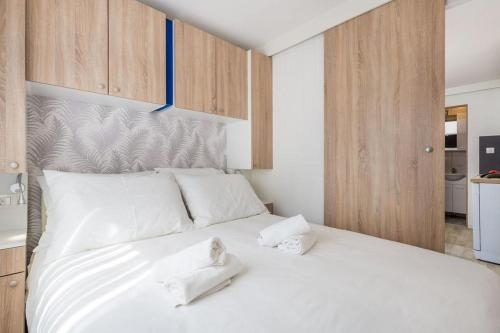 a bedroom with a large white bed with wooden cabinets at Mini camping FUNTANA in Poreč