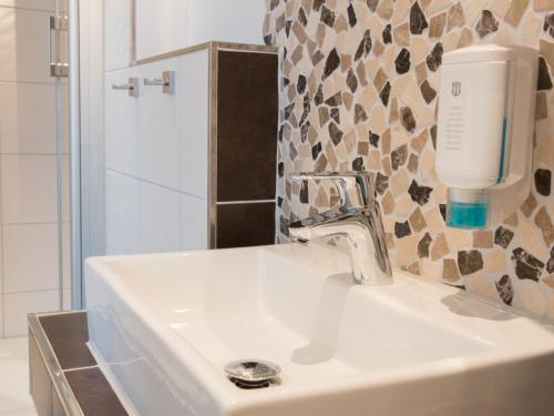a white bathroom sink with a soap dispenser on it at Ducky’s Restaurant | Events | Hotel in Bad Nauheim