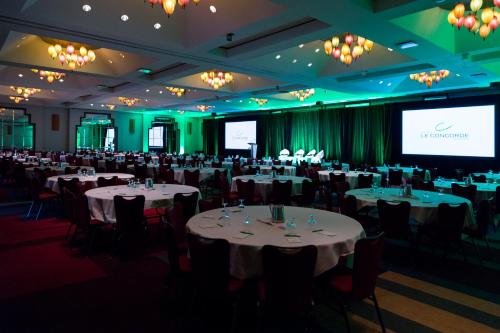 a conference room with tables and chairs and a screen at Hôtel Le Concorde Québec in Quebec City