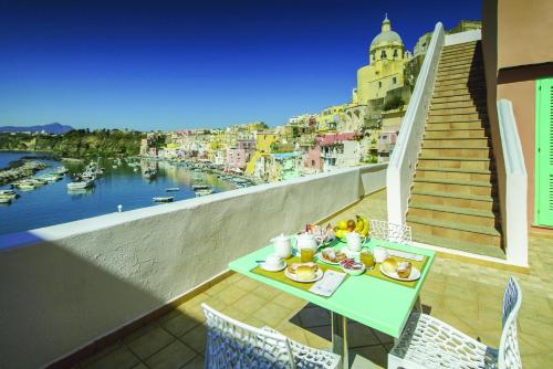 uma mesa com comida numa varanda com vista para a água em Hotel La Corricella em Procida