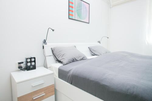 a white bedroom with a bed and a night stand at Maksimir-Rebro in Zagreb
