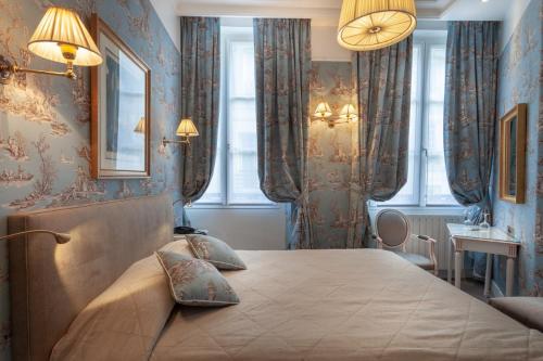 a bedroom with a large bed with blue wallpaper at Grand Hôtel de L'Univers Saint-Germain in Paris