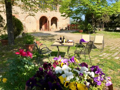 uma mesa e cadeiras num quintal com flores em Agriturismo La Roverella em Monteroni dʼArbia