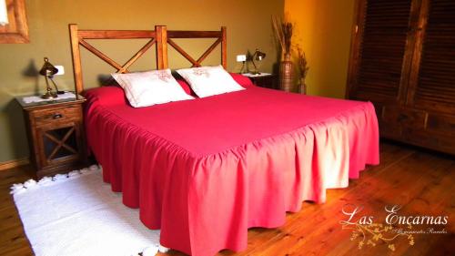 a bedroom with a bed with a red blanket at Las Encarnas in Braojos de la Sierra