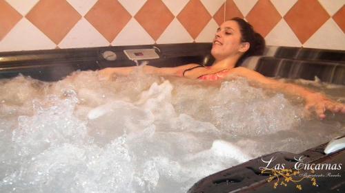 Eine Frau sitzt in einer Whirlpool-Badewanne in der Unterkunft Las Encarnas in Braojos de la Sierra