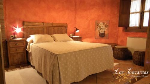 a bedroom with a bed in a room with orange walls at Las Encarnas in Braojos de la Sierra