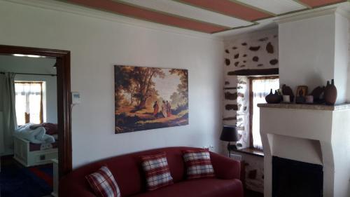 a living room with a red couch and a painting on the wall at Vernon Villa Stone 1887 in Kastoria