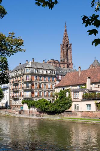 a building next to a river with a clock tower at Novotel Strasbourg Centre Halles in Strasbourg