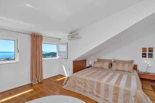 a white bedroom with a bed and two windows at Apartment Manhattan in Makarska